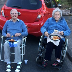 Two people sitting outside with meals on their laps