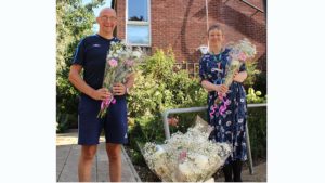 Two people holding flowers outside Treetops hospice