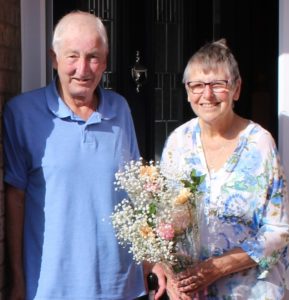 Couple in doorway smiling with flowers
