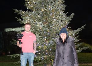 two people smiling in front of a Christmas tree