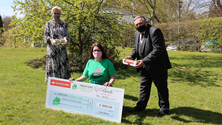 People in garden holding cheque