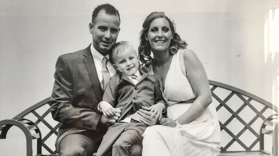 Black and white image of smiling couple and son on their wedding day