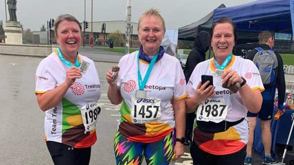 Three ladies with running medals smiling