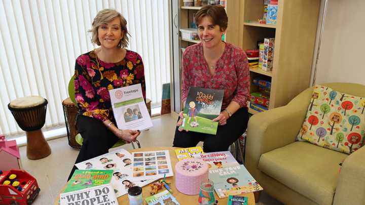 Two women smiling with counselling training materials