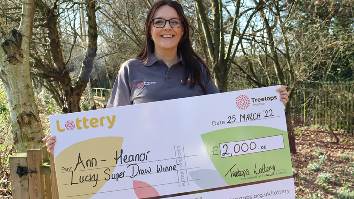 Woman smiling holding Lottery Super Draw cheque