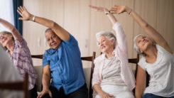 Older people sitting on chairs doing arm exercises