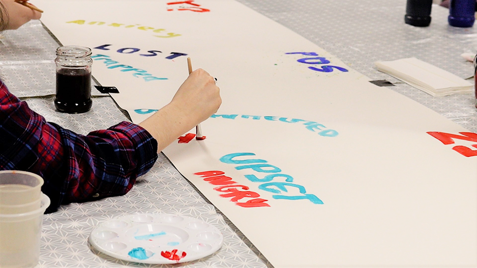 Child's hand painting words about grief