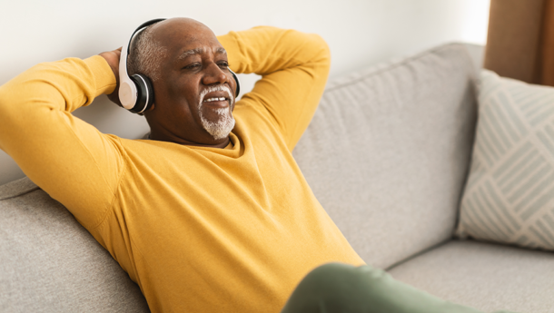Happy man listening to podcast through headphones