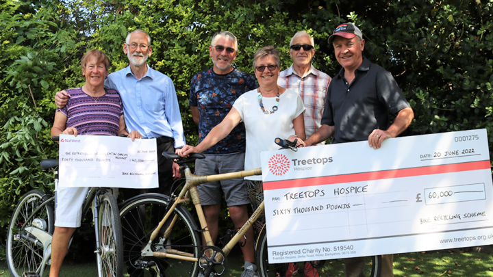 Group of people smiling with bikes and big cheques
