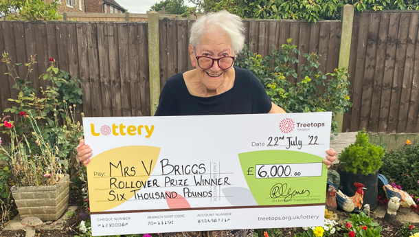 Lady smiling with winning Treetops lottery cheque