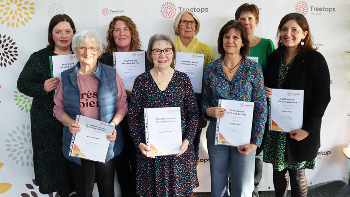 Group of smiling volunteers and staff with long service awards
