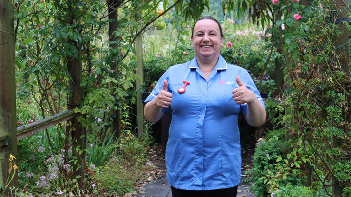 Treetops Hospice nurse in uniform smiling and giving a thumbs up