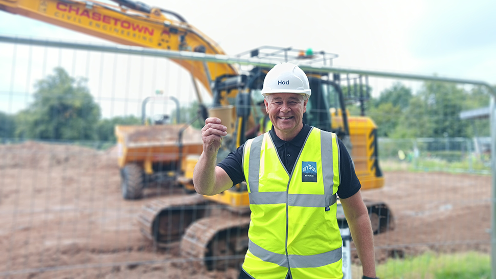 Man holding cup of tea in front of digger
