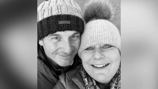 Black and white photo of couple in winter hats smiling on blurred background
