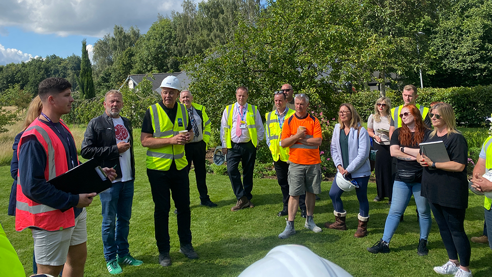 Group of people wearing high-viz vests and hard hats getting a briefing
