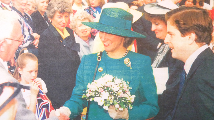 Old colour photo of lady in turquoise holding flowers shaking hands