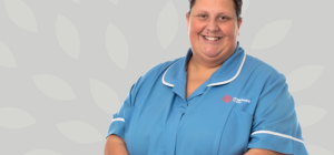 A Treetops Hospice Nurse in her blue uniform smiling at the camera