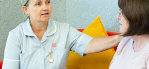 A Treetops Hospice Nurse sat on a sofa talking to another lady