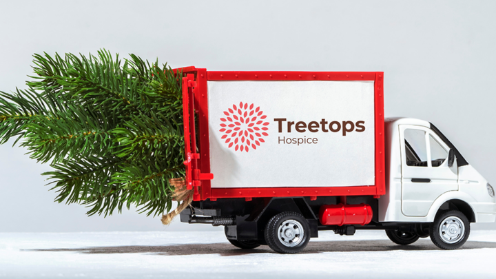 Red truck with Treetops logo carrying a Christmas tree on its top