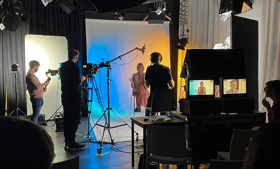 Film studio setting with students filming a woman in a chair