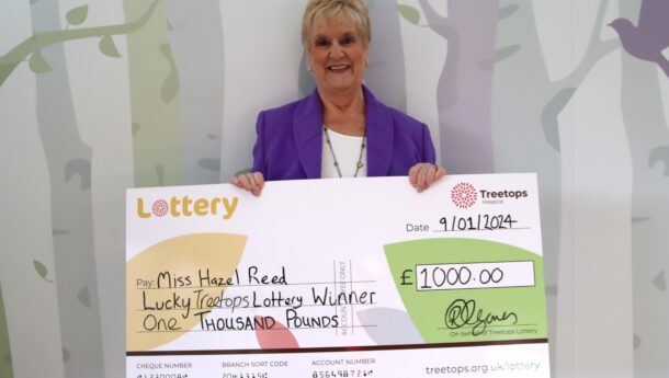 smiling white woman holding winning lottery cheque
