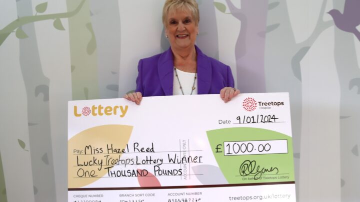 smiling white woman holding winning lottery cheque