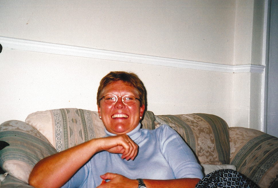 Woman with glasses sitting on a couch and smiling