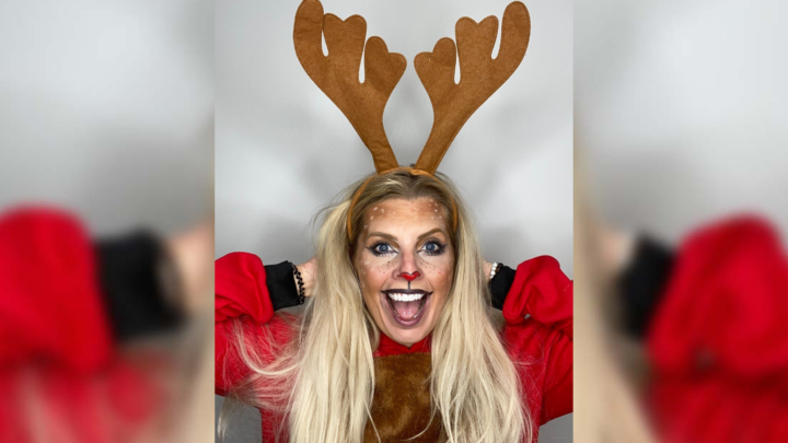 Young white woman with long blond hair wearing reindeer antlers and face make up, smiling