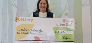 Woman smiling holding Super Draw winner cheque