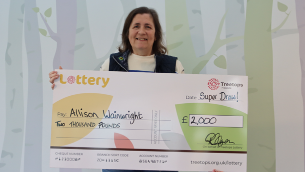 Woman smiling holding Super Draw winner cheque