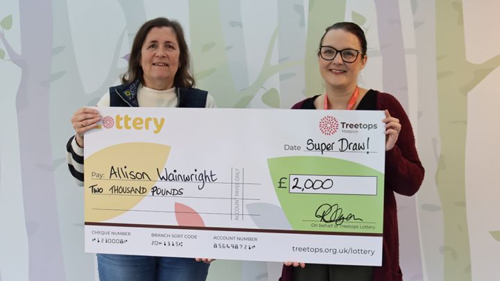 two women smiling holding a giant Treetops Super Draw cheque for £2000