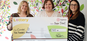 Three women smiling holding a giant cheque showing they are winners of the Treetops Super Draw