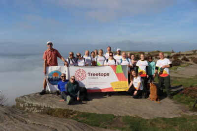 a large group of people wearing Treetops tops holding a big Treetops banner