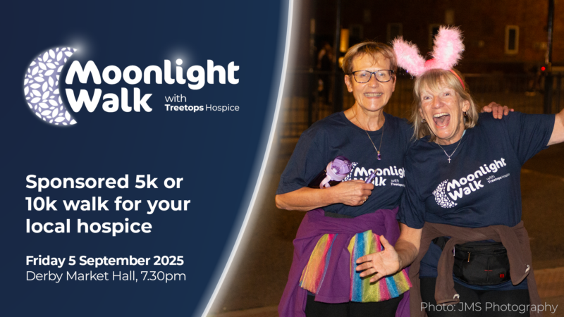 Two women wearing Moonlight Walk shirts and fun accessories smile, promoting a sponsored walk event for Treetops Hospice at Derby Market Hall on 5 September 2025.