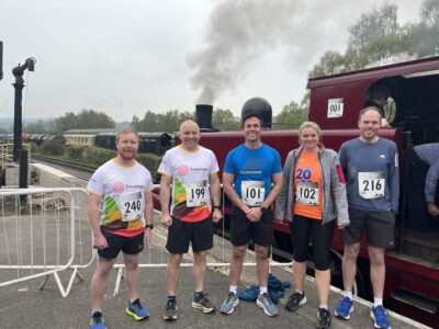 5 people in running gear standing in front of a train