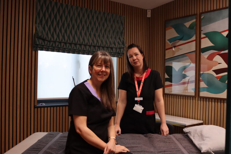 Two women smiling in a complementary therapy room.