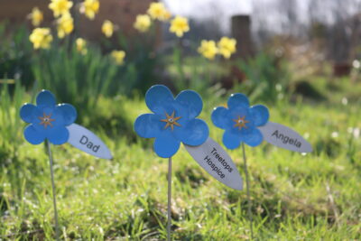 3 blue metal flowers surrounded by grass