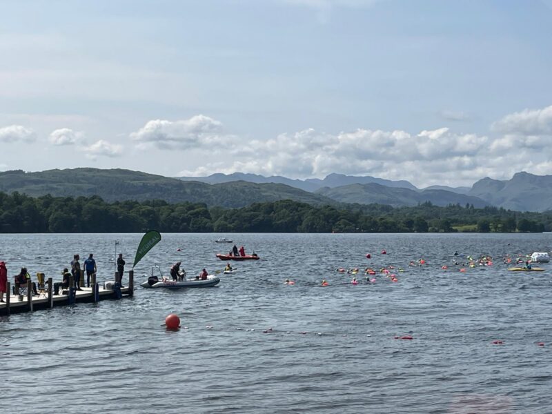 A big open lake with swimmers and people in paddle boats.