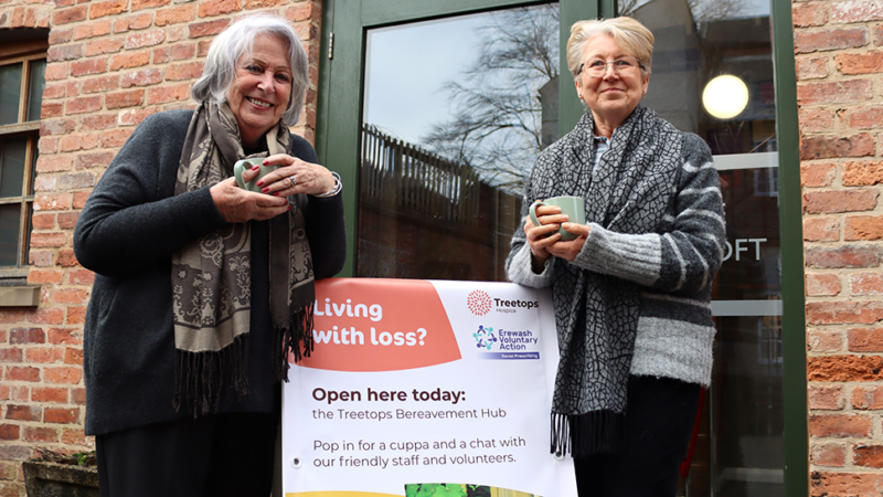 Two smiling volunteers stood outside of a Treetops Bereavement Hub.