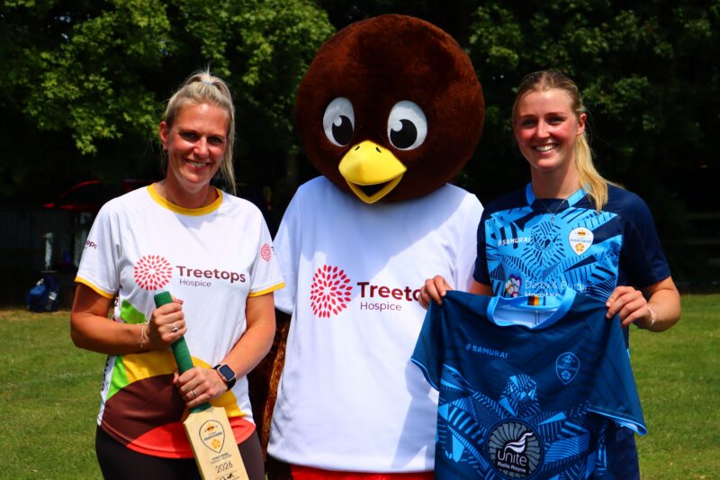 Two women smiling with Remy, the Treetops Hospice mascot.