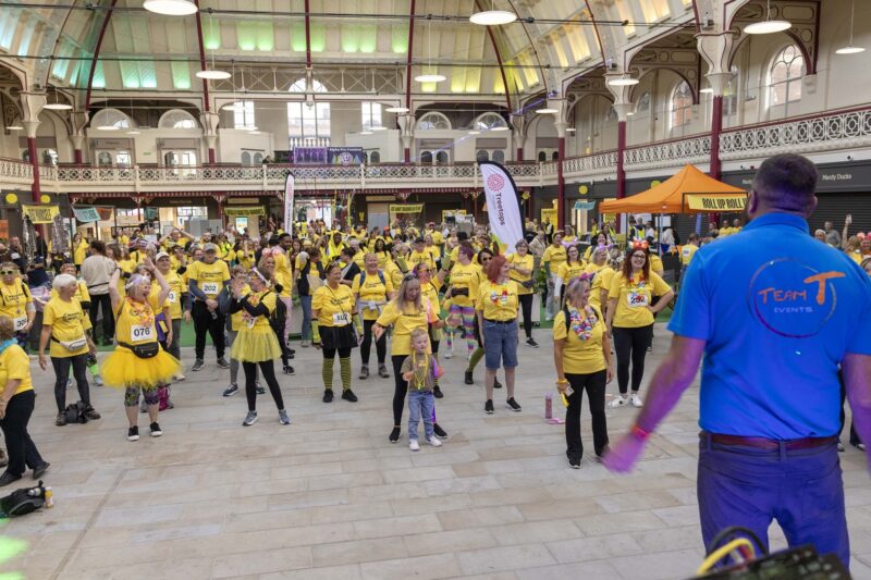 A large group of people in yellow t-shirts following a warm up.