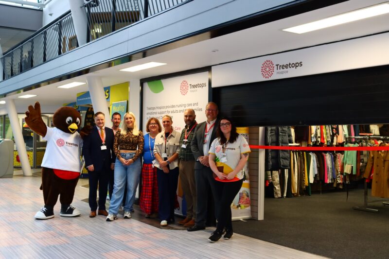 The Treetops Hospice team stoof in front of the new shop, smiling.
