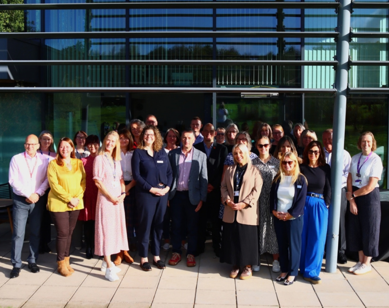 A group of hospice professionals stood outside in the sun.