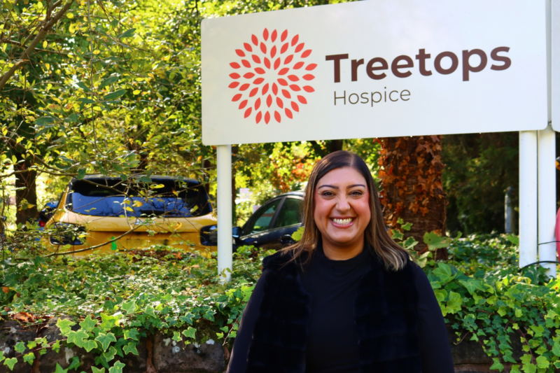 A woman stood in front of Treetops Hospice sign.